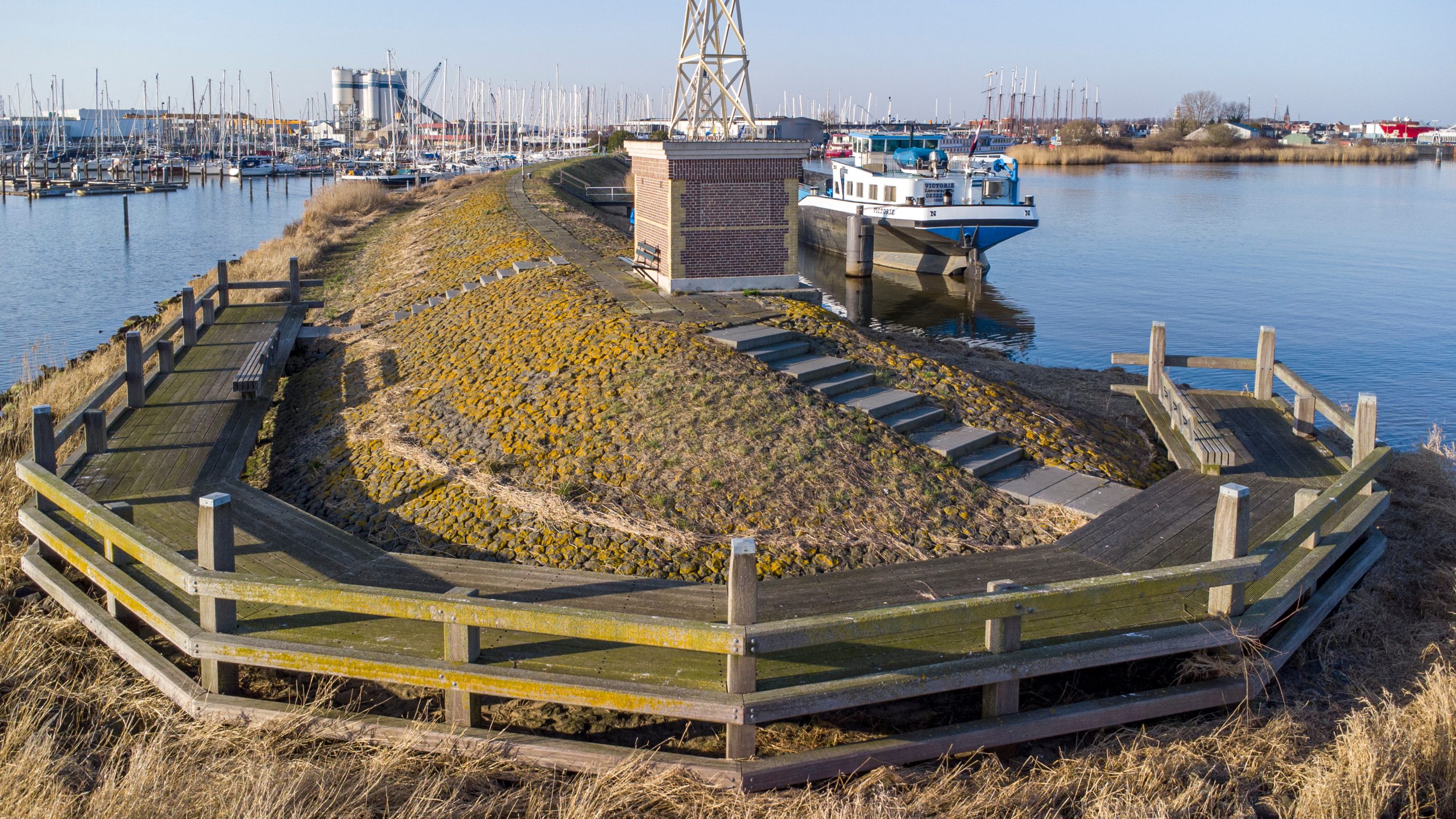 Afgewerkte oeverconstructie met houten beschoeiing en natuurvriendelijke oever in jachthaven.