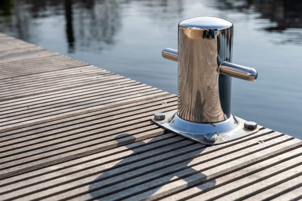 Glanzende roestvrijstalen meerpaal op houten steiger aan het water, professioneel gemonteerd.