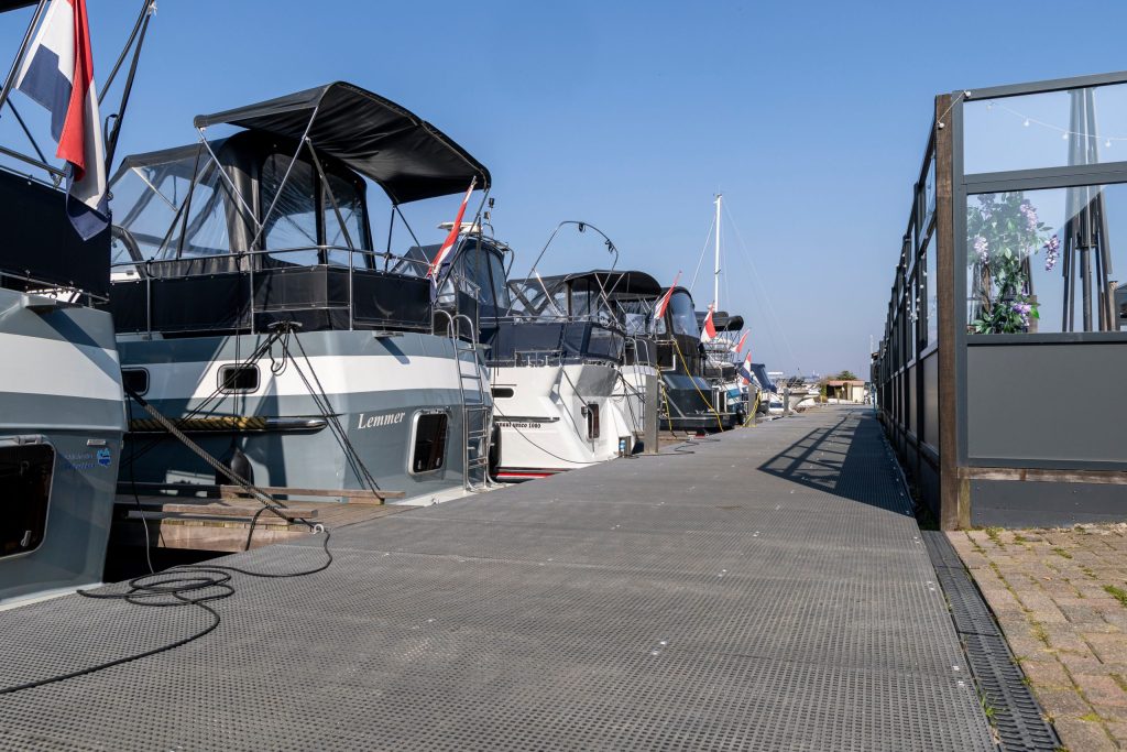 Moderne vlottende steiger met afgemeerde motorboten in een jachthaven op een zonnige dag.