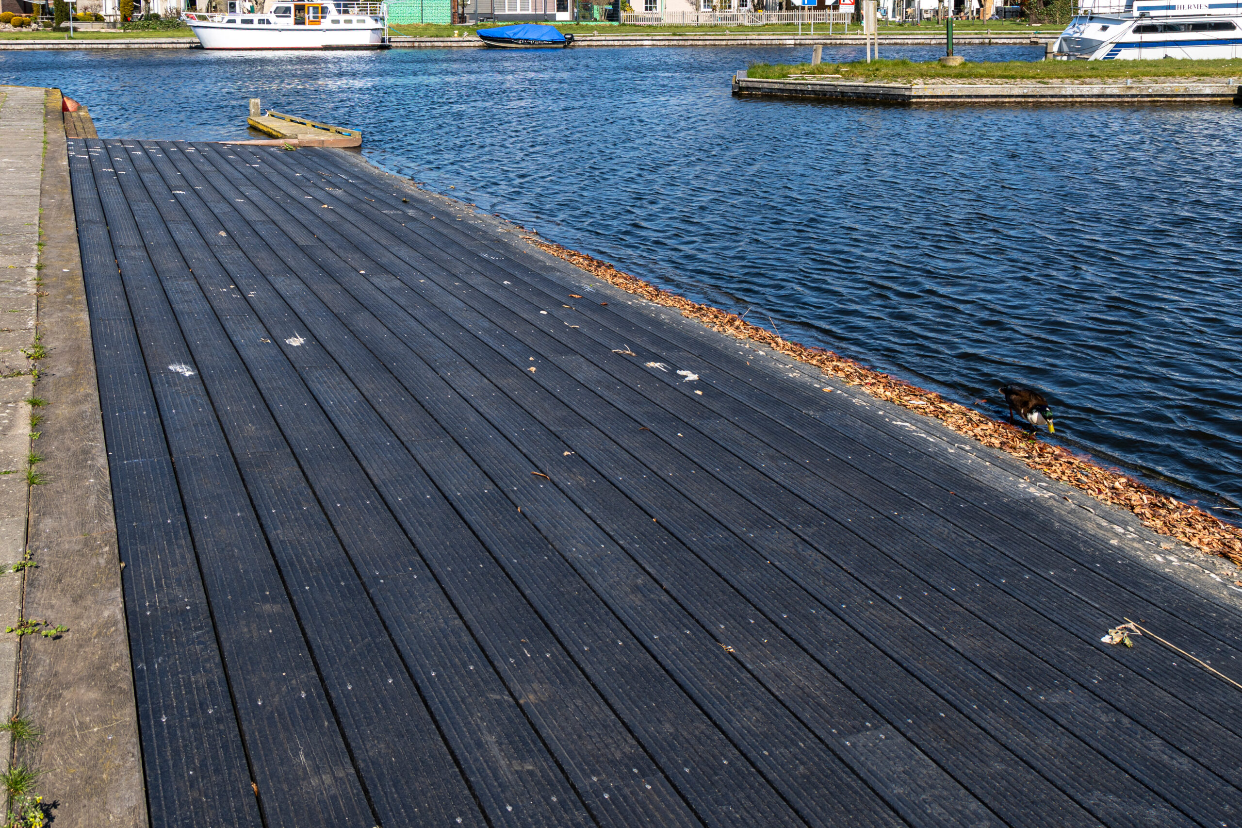 Zwarte hardhouten steiger langs het water met planken constructie, aangelegd door Bouma Waterwerken.