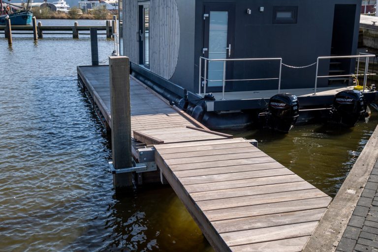 Houten drijvende steiger met aluminium palen bij woonboot in jachthaven, aangelegd door Bouma Waterwerken.
